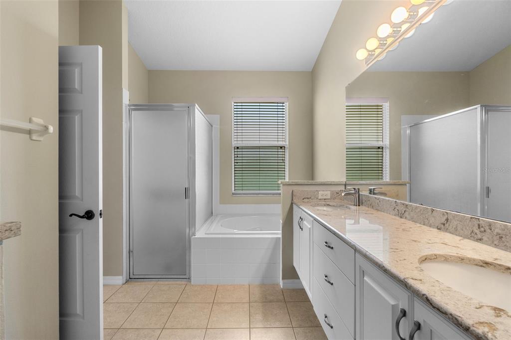 890 Summit Greens Boulevard Clermont, FL 34711 - Photo 25 of 62 a spacious bathroom with a granite countertop sink mirror and a bathtub