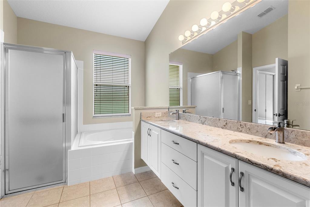 890 Summit Greens Boulevard Clermont, FL 34711 - Photo 26 of 62 a bathroom with a granite countertop double vanity sink a mirror and a bathtub