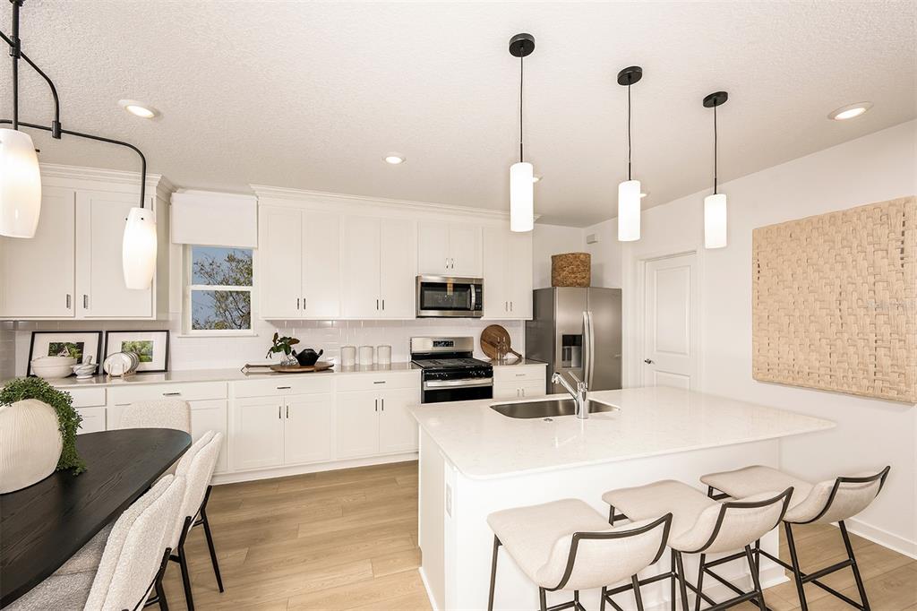 6283 Broad Fld Avenue Apollo Beach, FL 33572 - Photo 4 of 24 a kitchen with stainless steel appliances kitchen island granite countertop a sink a stove and chairs