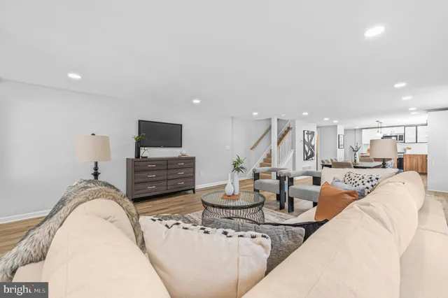 a living room with furniture a flat screen tv and kitchen view