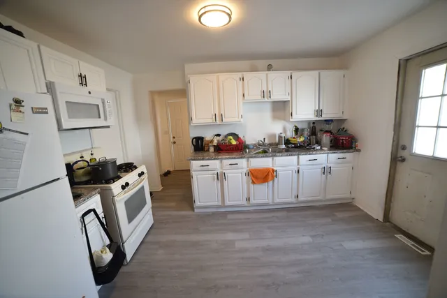 a kitchen with white cabinets a sink stove and refrigerator
