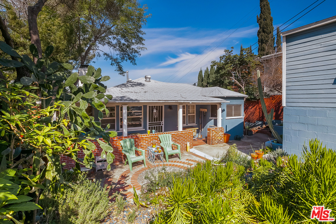 a backyard of a house with table and chairs under an umbrella