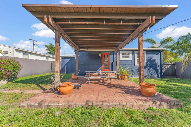a view of a backyard with table and chairs potted plants and large tree