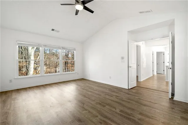 an empty room with wooden floor and windows