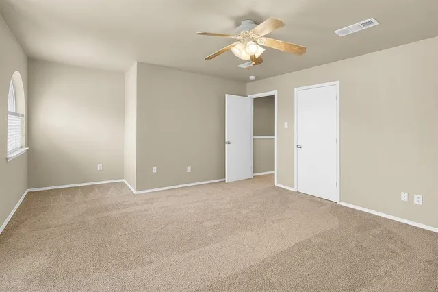 an empty room with a ceiling fan and a window