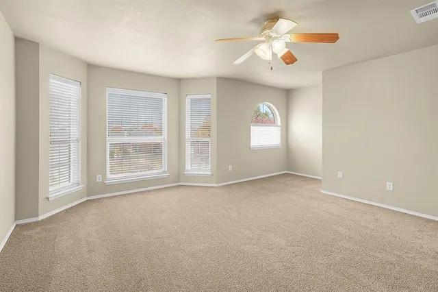 an empty room with windows and chandelier fan