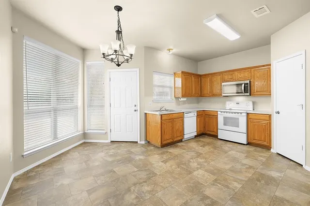 a large kitchen with stainless steel appliances granite countertop a stove a sink dishwasher a refrigerator and a granite counter tops