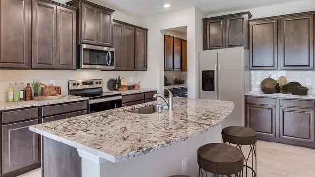 a kitchen with stainless steel appliances granite countertop a sink a stove and refrigerator