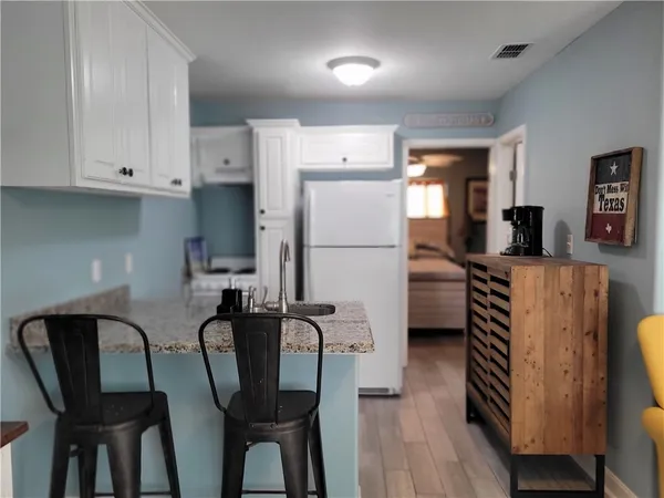 a kitchen with stainless steel appliances a refrigerator a stove a dining table and chairs with wooden floor