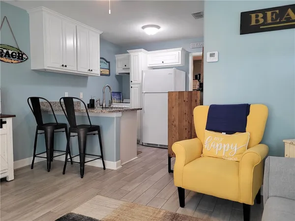a living room with stainless steel appliances furniture and a wooden floor