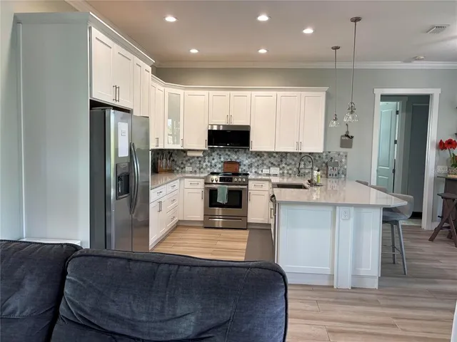 a kitchen with stainless steel appliances granite countertop a stove a sink a refrigerator and a granite counter tops with white cabinets