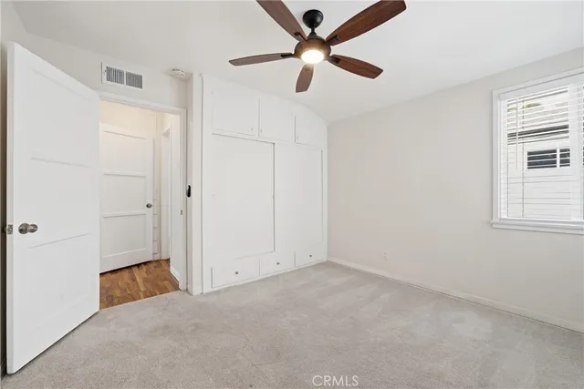 an empty room with windows and fan