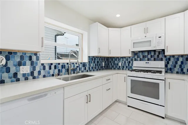 a kitchen with granite countertop white cabinets and white appliances