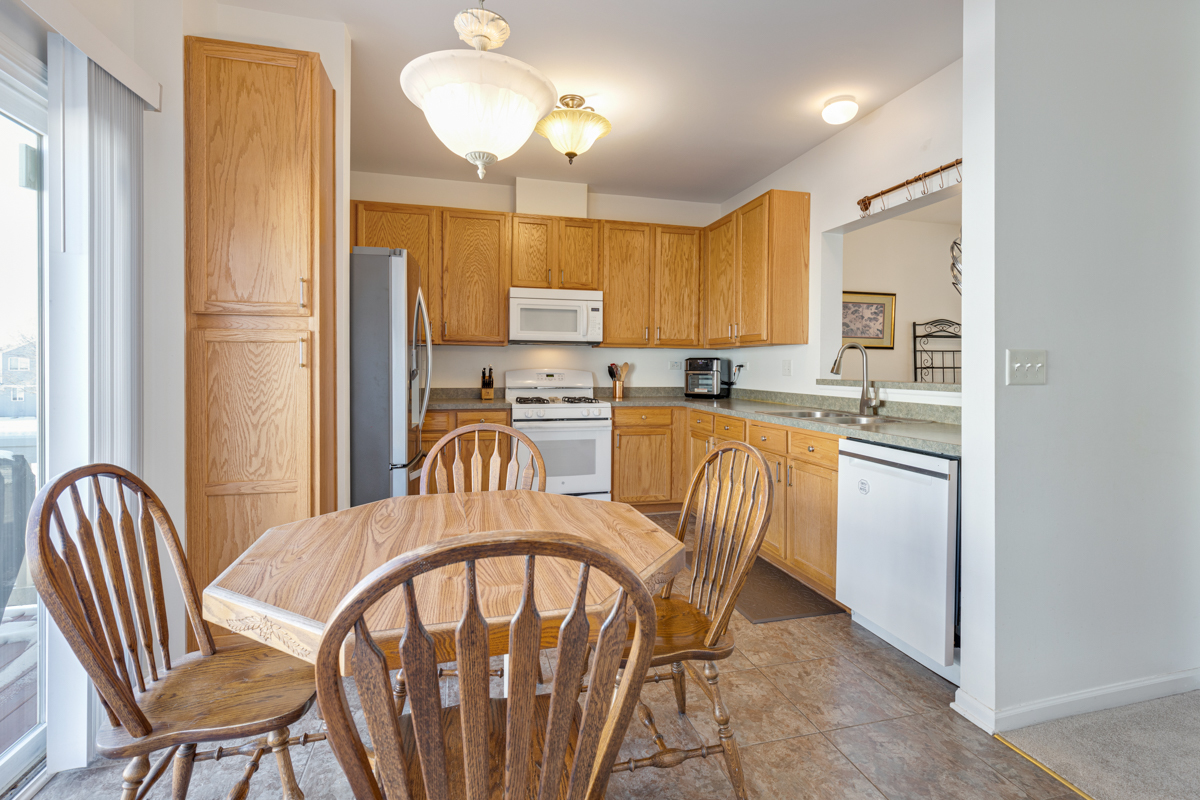 232 New Haven Drive Cary, IL 60013 - Photo 13 of 25 a kitchen with stainless steel appliances granite countertop a stove a refrigerator a dining table and chairs with wooden floor