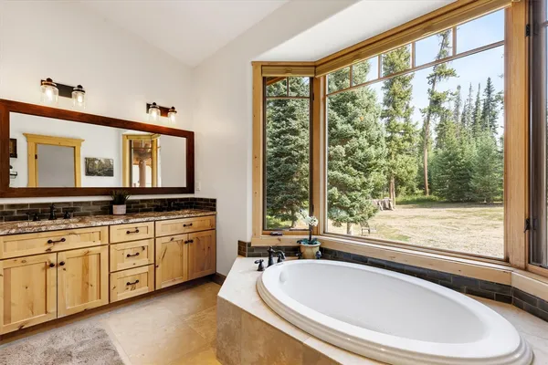 a bathroom with a granite countertop tub and a large window