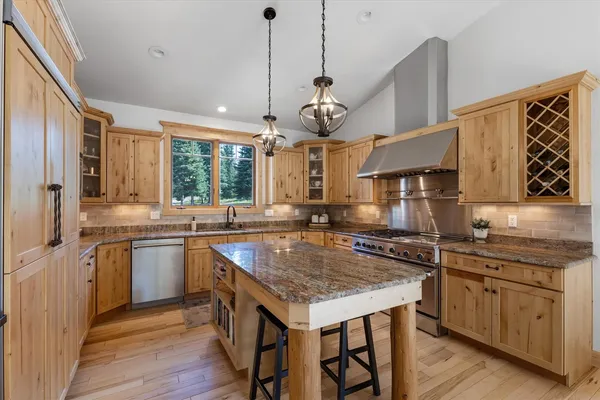 a kitchen with a stove a sink a center island and wooden floor