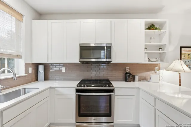 a kitchen with stainless steel appliances white cabinets and a stove top oven