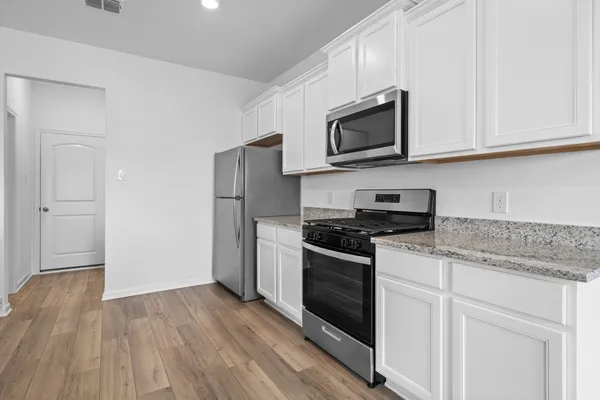 a kitchen with stainless steel appliances granite countertop a stove a microwave and a white cabinets
