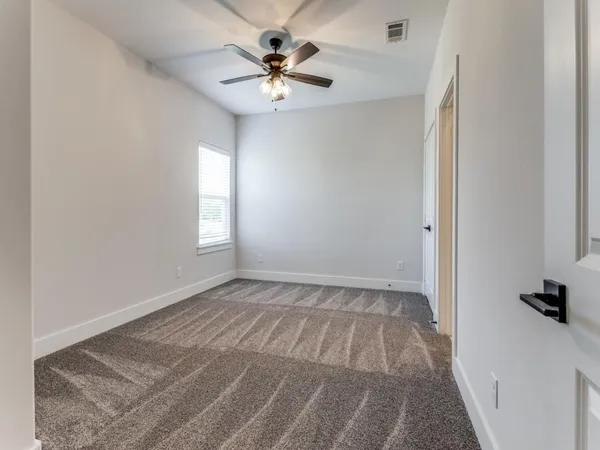 an empty room with windows and fan