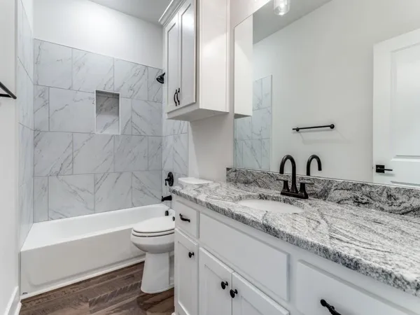 a bathroom with a granite countertop sink mirror toilet and bathtub