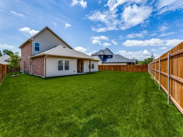 a view of a house with a big yard potted plants and large tree