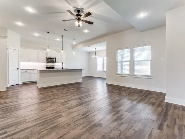 a view of a kitchen with kitchen island a sink wooden floor and a window