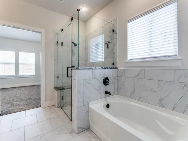 a bathroom with a bathtub a window and a shower