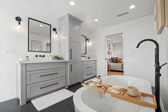 a bathroom with a granite countertop sink mirror and bathtub
