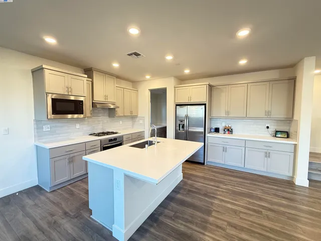 a large kitchen with stainless steel appliances kitchen island a stove a sink a microwave and a refrigerator