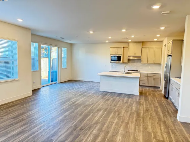 a large white kitchen with wooden floors and stainless steel appliances