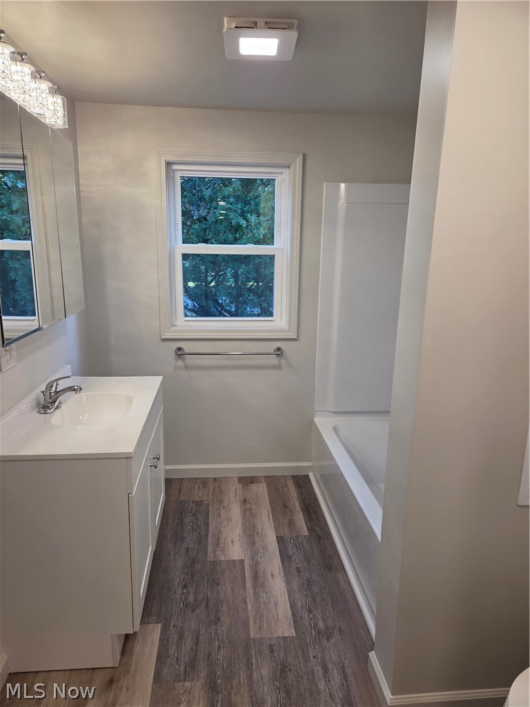 6145 Virginia Road Nashport, OH 43830 - Photo 16 of 24 White vanity with an integrated sink, wood-finish flooring, and a white bathtub