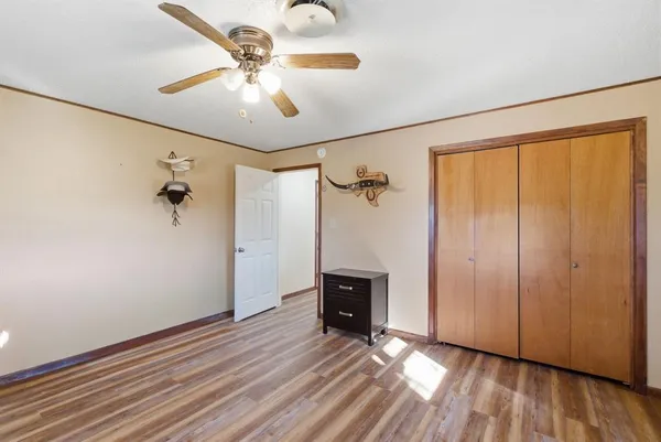 an empty room with wooden floor closet and windows