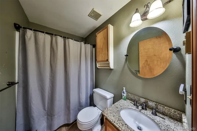 a bathroom with a granite countertop sink mirror vanity and toilet