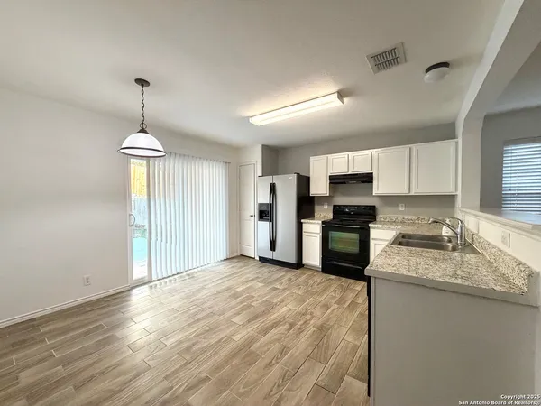 a kitchen with granite countertop a refrigerator oven a sink and dishwasher