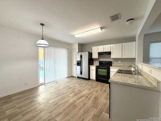 a kitchen with granite countertop a refrigerator oven a sink and dishwasher