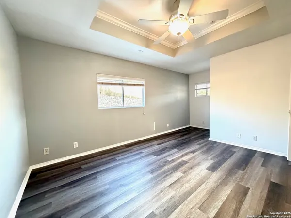 an empty room with wooden floor and fan