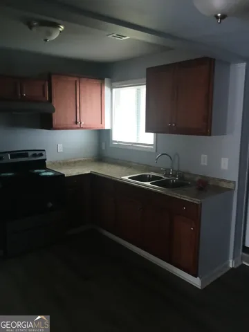 a kitchen with granite countertop stainless steel appliances a sink stove and cabinets