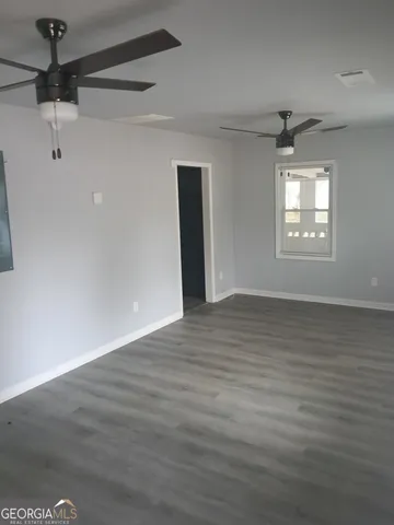 an empty room with wooden floor ceiling fan and windows