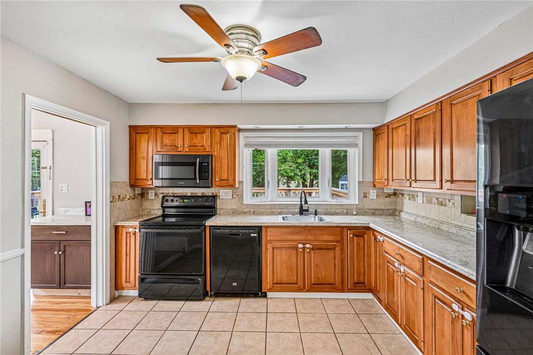 2428 Nottingham Road Bethlehem, PA 18017 - Photo 16 of 48 A well-equipped kitchen features honey-toned cabinetry, light countertops, and a bay window overlooking lush greenery.