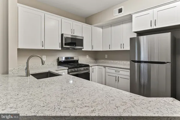 a kitchen with granite countertop a refrigerator sink and cabinets