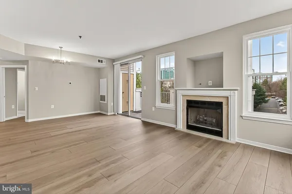 an empty room with wooden floor fireplace and windows