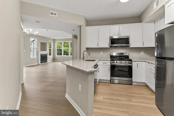 a kitchen with stainless steel appliances a stove top oven a sink dishwasher and a refrigerator with wooden floor