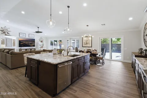 a kitchen with kitchen island granite countertop a sink a microwave a refrigerator and chairs