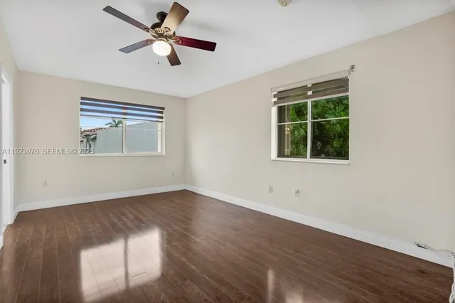 a view of empty room with wooden floor and fan