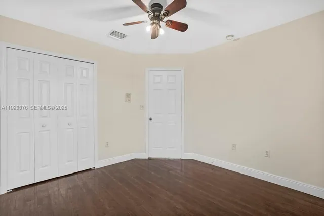 an empty room with wooden floor closet and ceiling fan