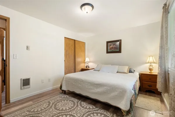 a bedroom with a bed dresser and a large window