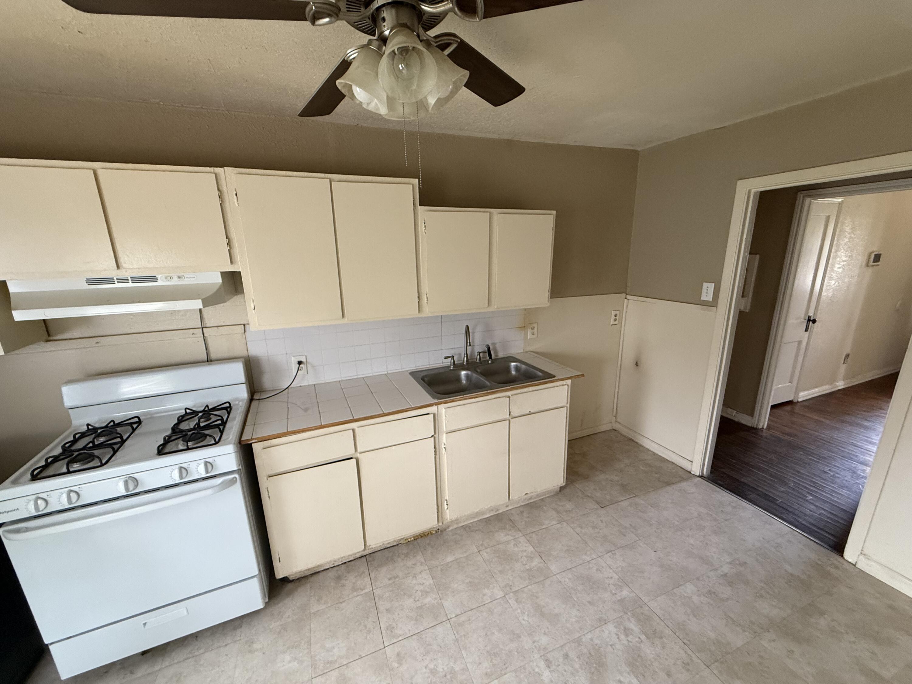 2416 31st Street Lubbock, TX 79411 - Photo 3 of 6 a kitchen with a stove and white cabinets