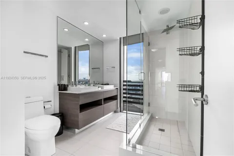 a bathroom with a granite countertop sink a toilet a mirror and shower