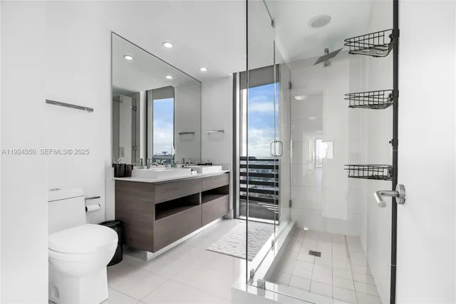 a bathroom with a granite countertop sink a toilet a mirror and shower
