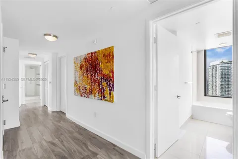 a view of a hallway with wooden floor and a living room